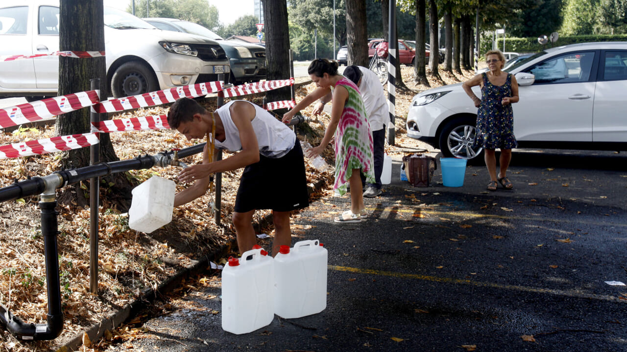 persone che si approvvigionano di acqua sana durante emergenza legionella a milano